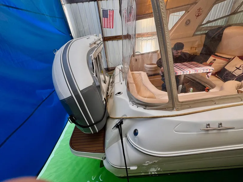 Slide: The Image of 2000 Sea Ray 310 Sundancer yacht with inflatable boat, docked indoors, American flag visible. - 8
