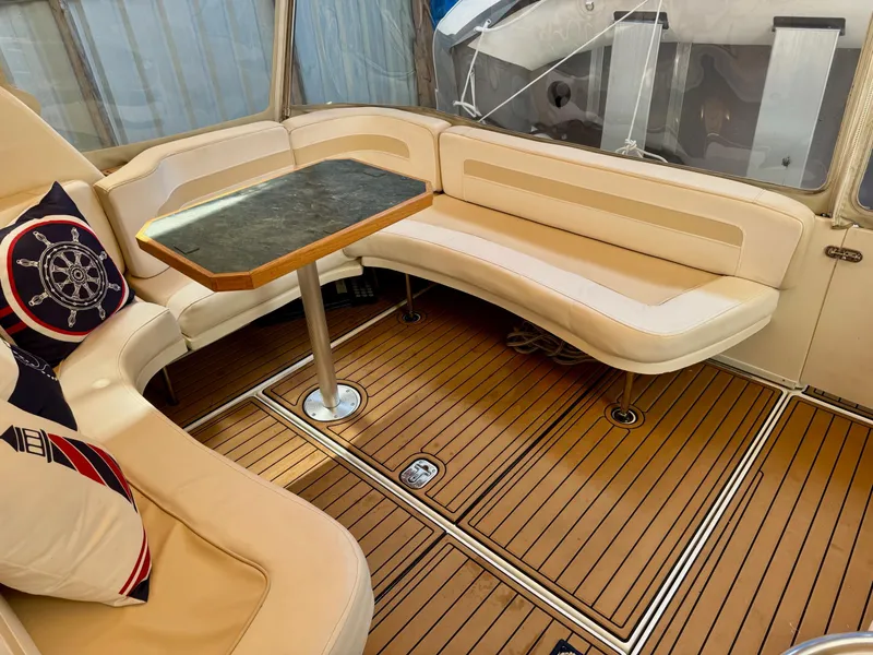 Slide: The Image of 2000 Sea Ray 310 Sundancer interior with beige seating and wooden flooring. - 9