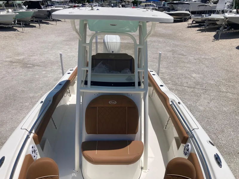 Slide: The Image of 2025 Key West 239FS boat with brown seating and white console, parked on gravel. - 11