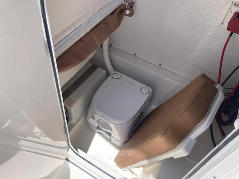 Slide: The Image of Portable toilet in 2025 Key West 239FS boat cabin, with brown cushions and white interior. - 15