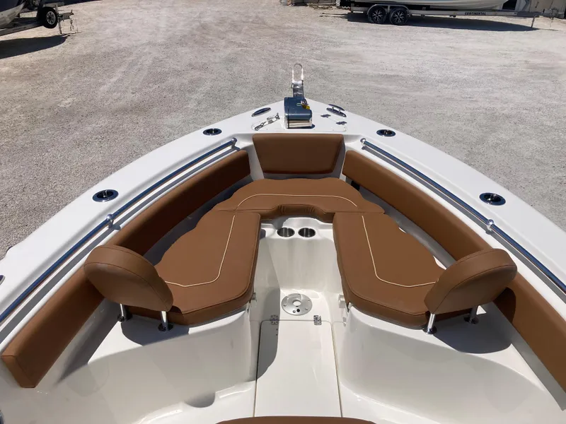 Slide: The Image of 2025 Key West 239FS boat with brown seating and white deck, parked on gravel. - 8