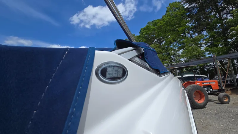 Slide: The Image of 2006 Crownline 262 EX boat with blue cover, parked outdoors under a clear sky. - 13