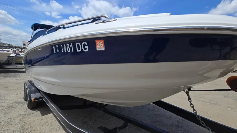 Slide: The Image of 2006 Crownline 262 EX boat on trailer, blue and white hull, parked outdoors. - 2