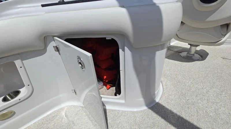 Slide: The Image of Open storage compartment on 2006 Crownline 262 EX boat, revealing life jackets inside. - 36