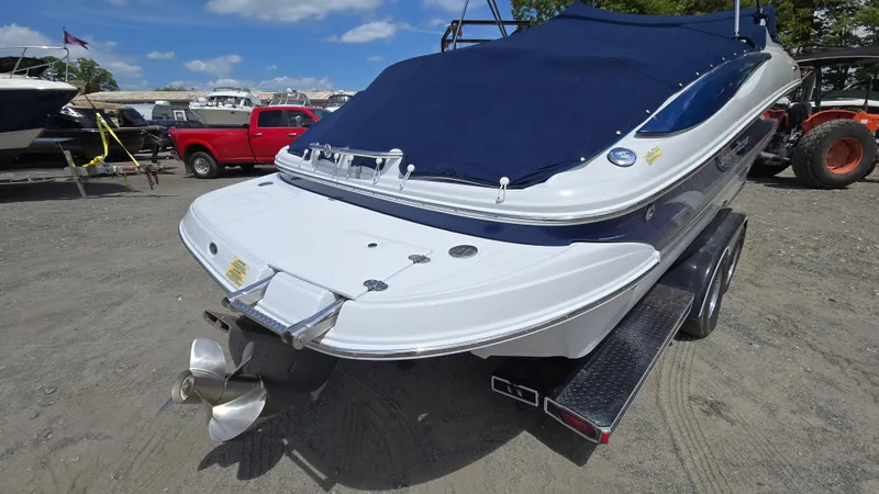 Slide: The Image of 2006 Crownline 262 EX boat with blue cover on trailer, parked outdoors. - 4