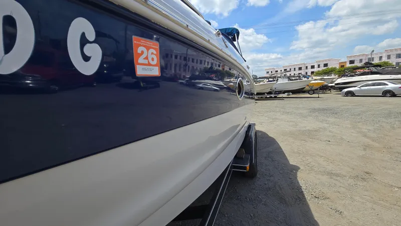 Slide: The Image of 2006 Crownline 262 EX boat parked on gravel lot under blue sky. - 7