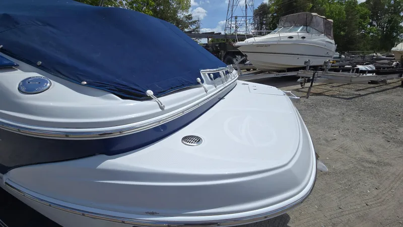 Slide: The Image of 2006 Crownline 262 EX boat with blue cover, parked on a trailer in a boatyard. - 9