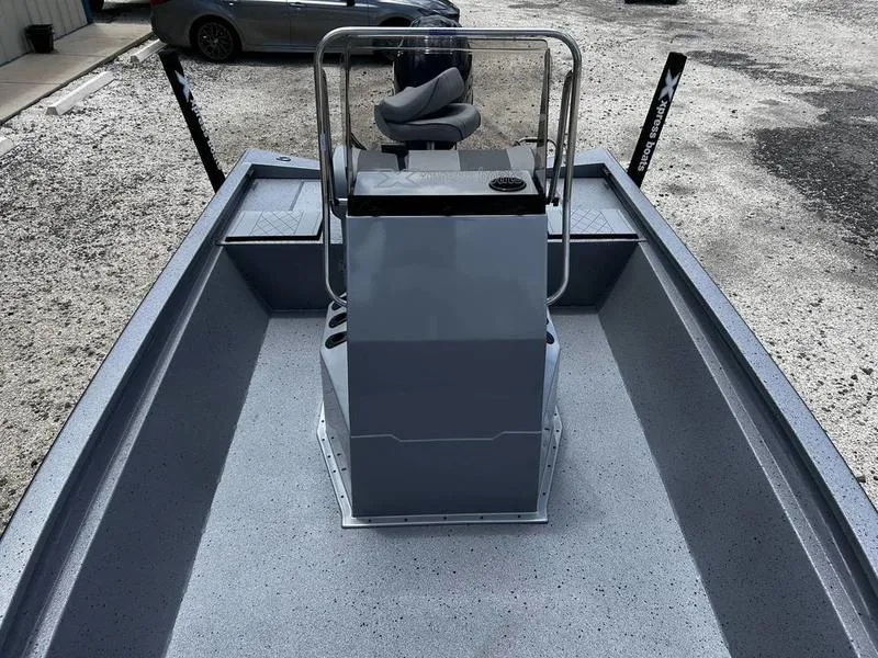 Slide: The Image of 2025 Xpress H190B boat interior with console and seating, parked on gravel. - 8