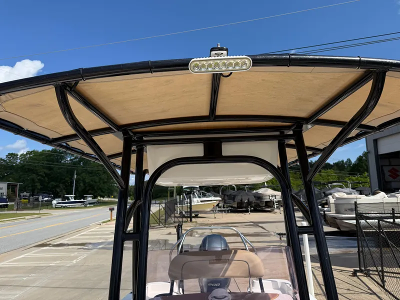 Slide: The Image of 2019 NauticStar 231 Hybrid boat with T-top canopy, parked outdoors under clear blue sky. - 13