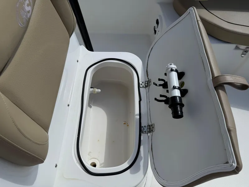 Slide: The Image of 2019 NauticStar 231 Hybrid boat storage compartment with beige seating and fishing rod holder. - 14