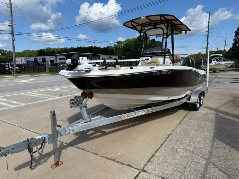 Slide: The Image of 2019 NauticStar 231 Hybrid boat on trailer, parked outdoors under a blue sky. - 2