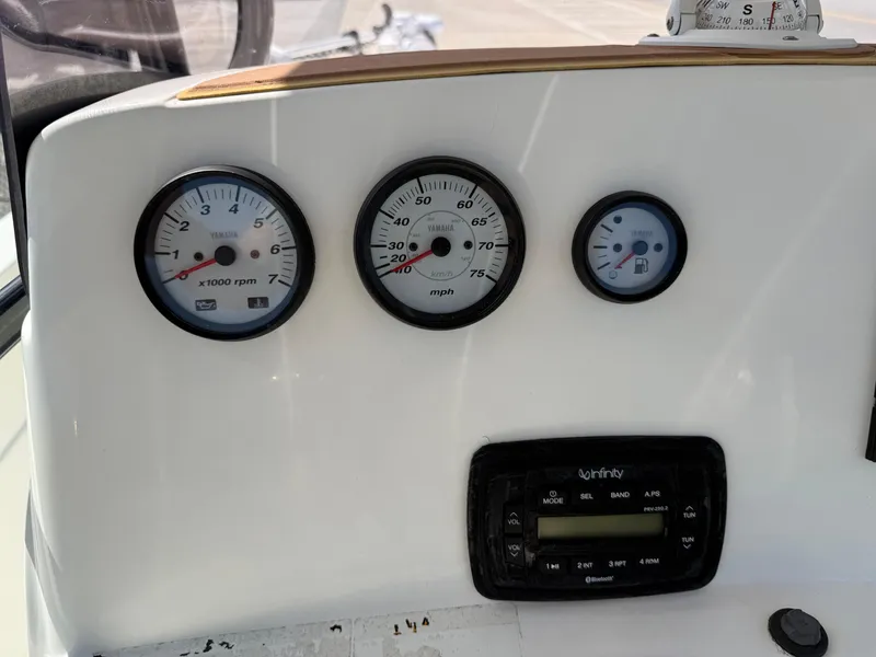 Slide: The Image of Dashboard of 2019 NauticStar 231 Hybrid boat with gauges and Infinity stereo system. - 23