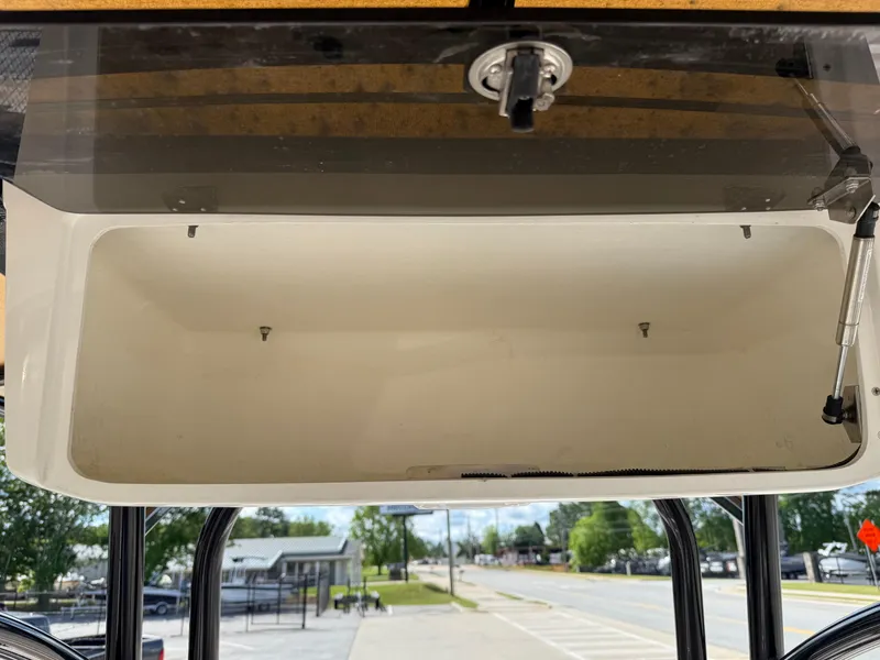 Slide: The Image of 2019 NauticStar 231 Hybrid storage compartment, open and empty, with street view in background. - 30