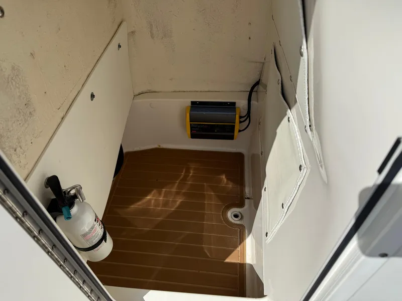 Slide: The Image of 2019 NauticStar 231 Hybrid interior storage compartment with fire extinguisher and equipment. - 32