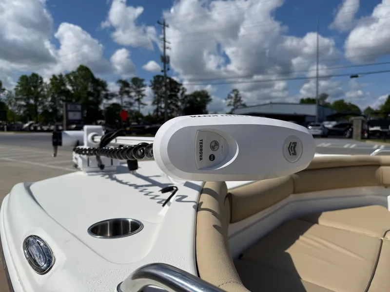 Slide: The Image of 2019 NauticStar 231 Hybrid boat with beige seating and trolling motor, under a partly cloudy sky. - 36