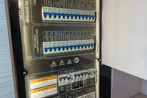 Slide: The Image of Electrical panel on a 2024 Axopar 45 boat, featuring circuit breakers and safety labels. - 23
