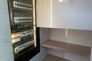 Slide: The Image of Electrical panel inside 2024 Axopar 45 boat, showcasing circuit breakers and storage shelves. - 24
