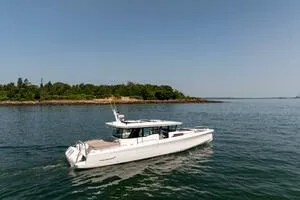 Slide: The Image of 2024 Axopar 45 XC Cross Cabin cruising on calm waters near a lush island. - 4