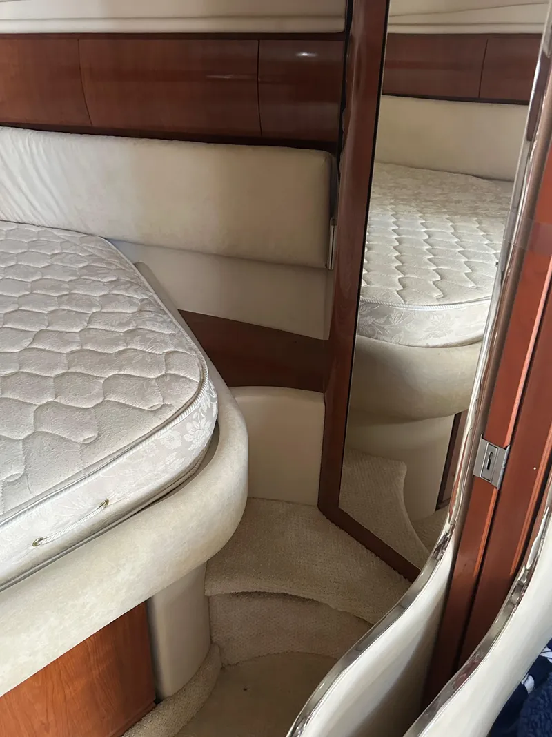 Slide: The Image of 2004 Sea Ray 360 Sundancer cabin interior with plush bedding and wooden accents. - 15
