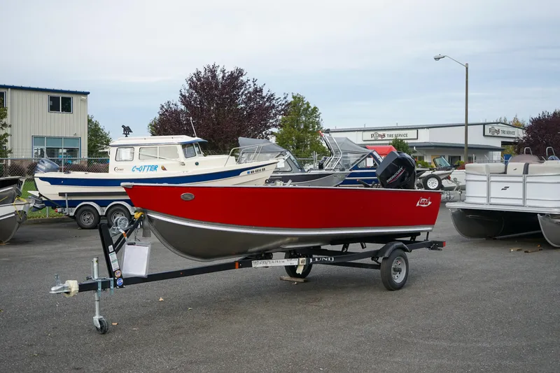 Slide: The Image of 2025 Lund 1600 Fury Tiller boat in red on a trailer, parked outdoors. - 0