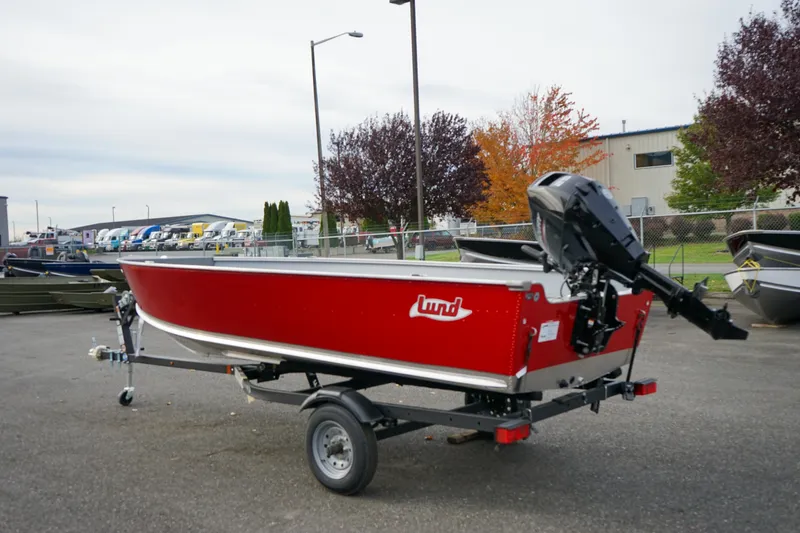 Slide: The Image of 2025 Lund 1600 Fury Tiller boat, red, on trailer, parked outdoors. - 2