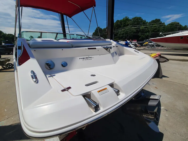 Slide: The Image of 2007 Regal 2200 Bowrider boat with red canopy, docked on a sunny day. - 17