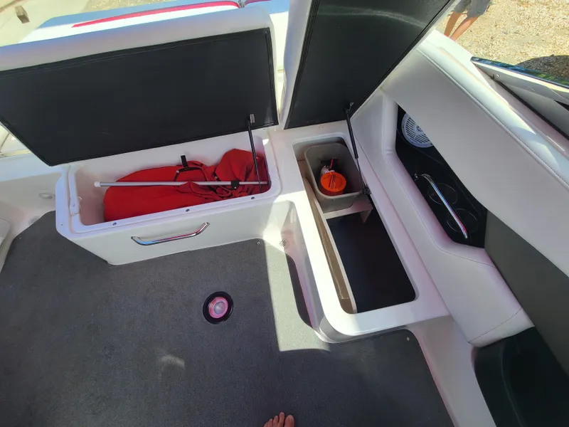 Slide: The Image of 2007 Regal 2200 Bowrider interior storage compartments with red life jacket and accessories. - 28