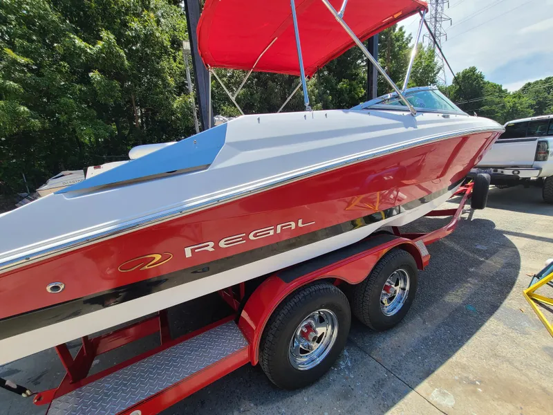 Slide: The Image of 2007 Regal 2200 Bowrider boat with red hull and trailer, parked outdoors. - 6