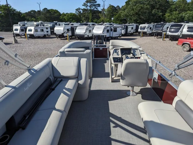 Slide: The Image of 2024 SunChaser Vista 22 LR pontoon boat interior with plush seating, parked near RVs. - 3