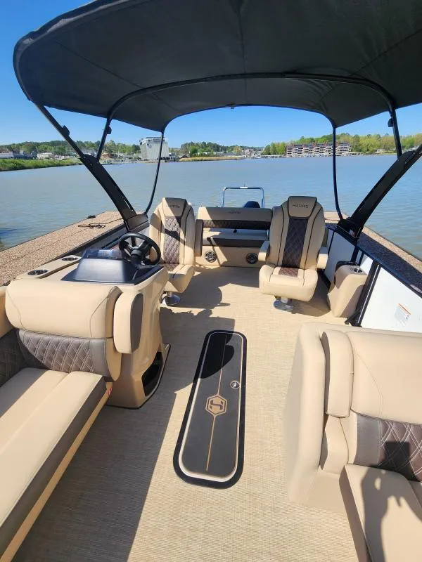 Slide: The Image of 2025 Harris Boats SUNLINER 230 interior with luxurious seating and canopy on a serene lake. - 10