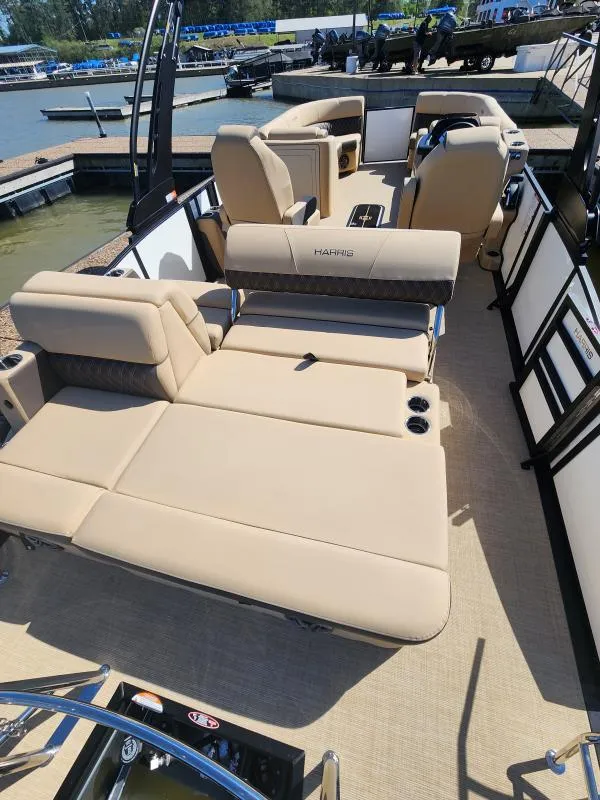 Slide: The Image of 2025 Harris Boats SUNLINER 230 interior with beige seating and cup holders, docked by the water. - 12