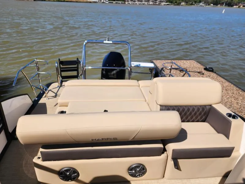 Slide: The Image of 2025 Harris Boats SUNLINER 230 with beige seating, overlooking a serene lake. - 16