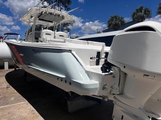Slide: The Image of 2013 Edgewater 388CC boat with outboard motor, docked under a clear blue sky. - 2