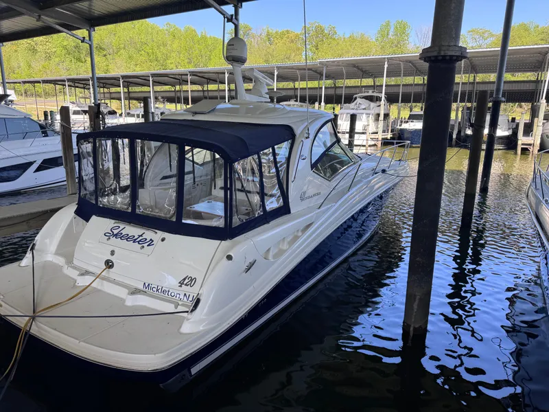 Slide: The Image of 2004 Sea Ray 420 Sundancer docked in a marina, featuring a sleek design and covered cockpit. - 14