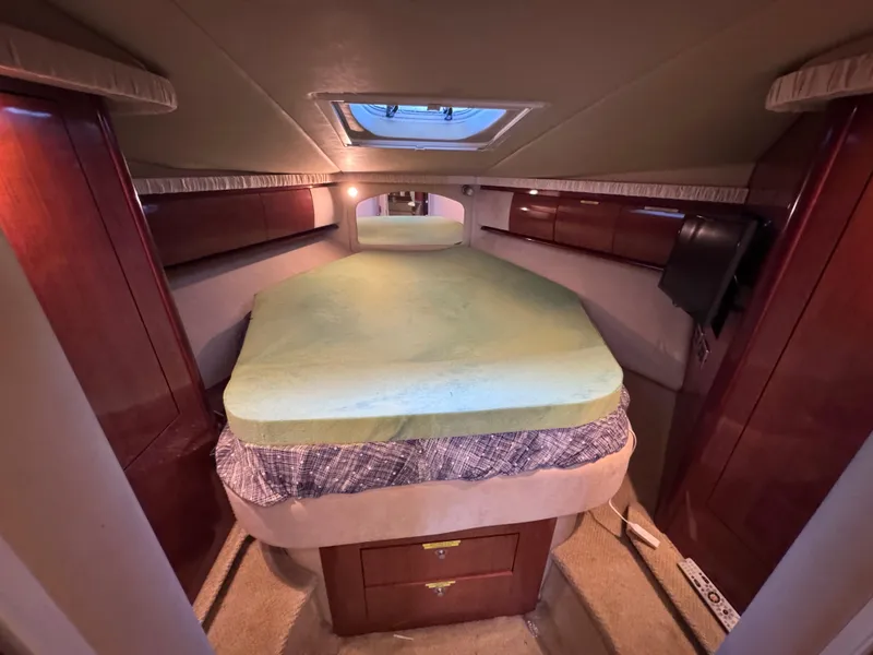Slide: The Image of 2004 Sea Ray 420 Sundancer cabin with bed, wooden cabinets, and overhead skylight. - 22