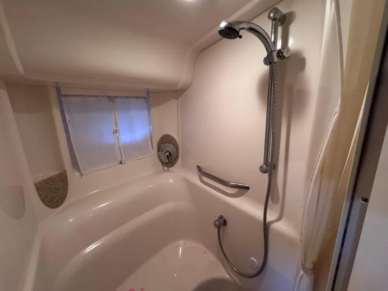 Slide: The Image of 2004 Sea Ray 420 Sundancer bathroom with shower, featuring a handheld showerhead and window. - 24