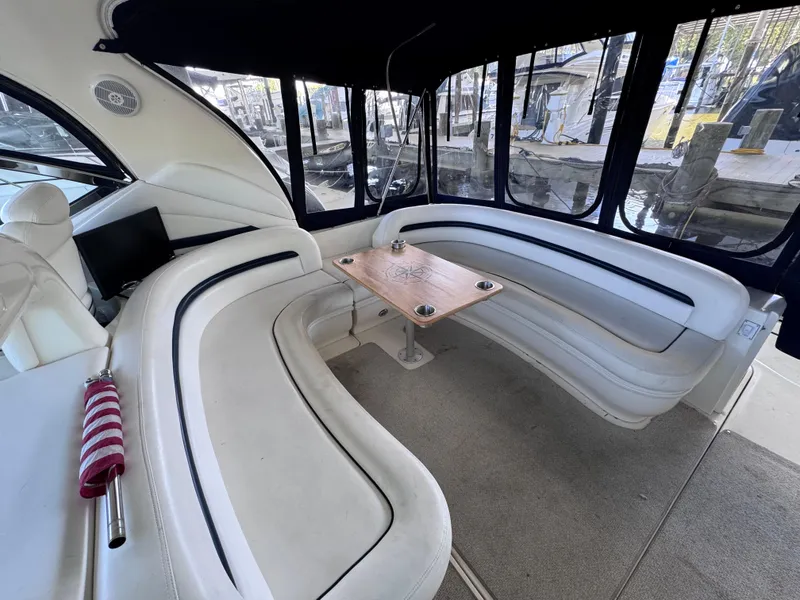 Slide: The Image of 2004 Sea Ray 420 Sundancer interior with curved seating and wooden table. - 5