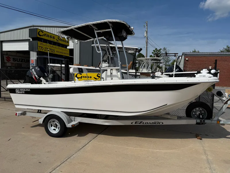 Slide: The Image of 2012 Carolina Skiff 19 Ultra boat on trailer, parked outside a shop. - 0