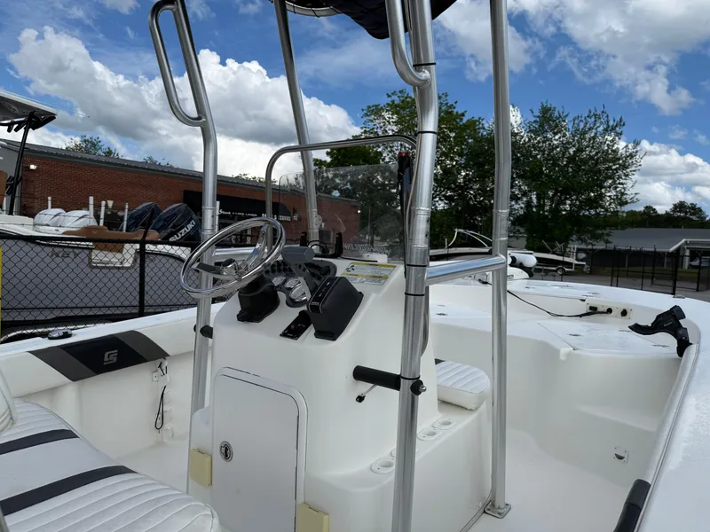 Slide: The Image of 2012 Carolina Skiff 19 Ultra boat interior with steering console and seating, under a blue sky. - 11