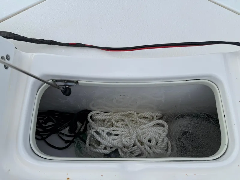 Slide: The Image of Storage compartment on a 2012 Carolina Skiff 19 Ultra, containing ropes and nets. - 17