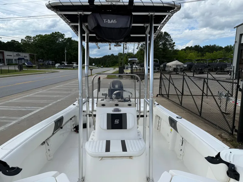 Slide: The Image of 2012 Carolina Skiff 19 Ultra boat with T-top, parked near a road and fence. - 18