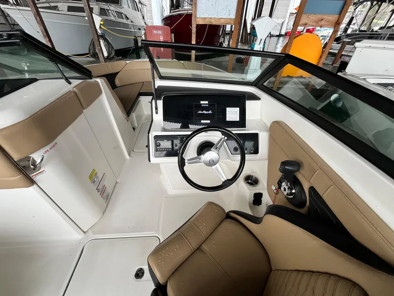 Slide: The Image of 2022 Sea Ray SPX 230 OB boat interior with steering wheel and beige seating. - 4