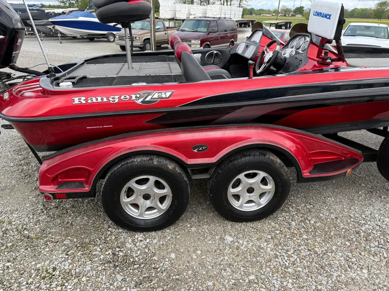 Slide: The Image of 2007 Ranger Z21 Comanche boat with red and black design on a gravel lot. - 10