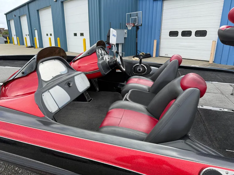 Slide: The Image of 2007 Ranger Z21 Comanche boat interior with red and black seats, parked near blue warehouse. - 6