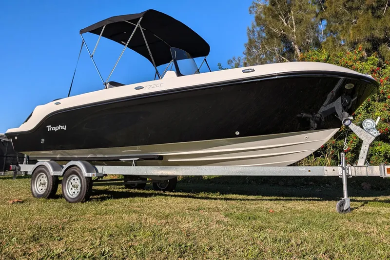 Slide: The Image of 2025 Bayliner Trophy T22CC boat on trailer, black and white design, sunny day. - 14