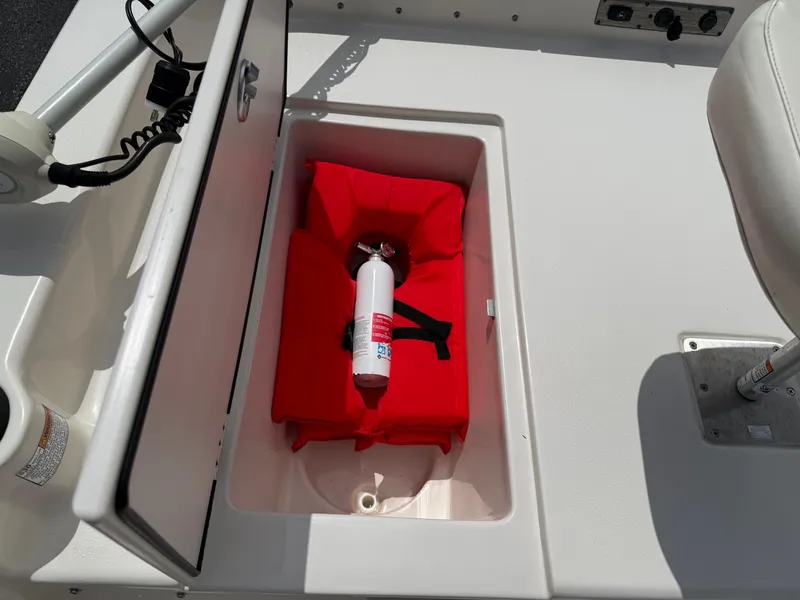 Slide: The Image of 2022 Carolina Skiff 21 LS boat storage compartment with fire extinguisher and red cushion. - 32