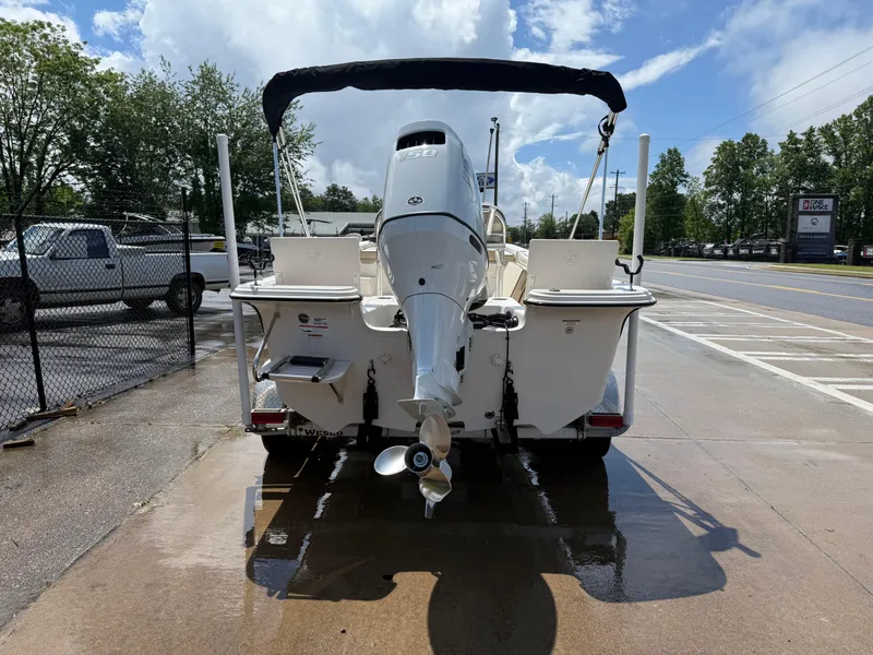 Slide: The Image of 2022 Carolina Skiff 21 LS boat with outboard motor, parked on wet pavement under a blue sky. - 6