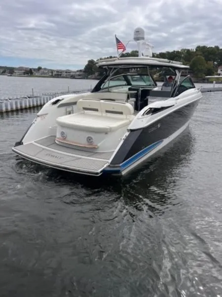 Slide: The Image of 2019 Cobalt A40 boat on water, rear view, with American flag, cloudy sky. - 9