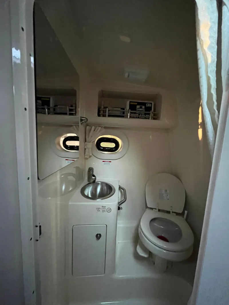 Slide: The Image of 2014 Sea Ray 260 Sundancer bathroom with sink, toilet, and storage shelves. - 13