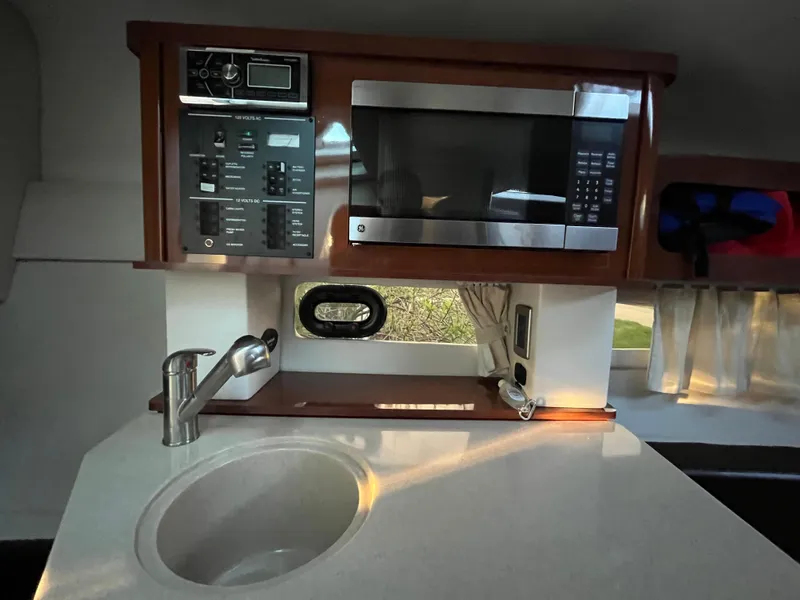Slide: The Image of 2014 Sea Ray 260 Sundancer galley with sink, microwave, and control panel. - 14